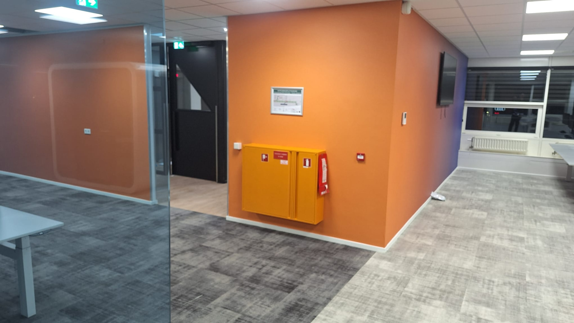 Strak afgewerkte oranje kantoorwand met brandslanghaspel
