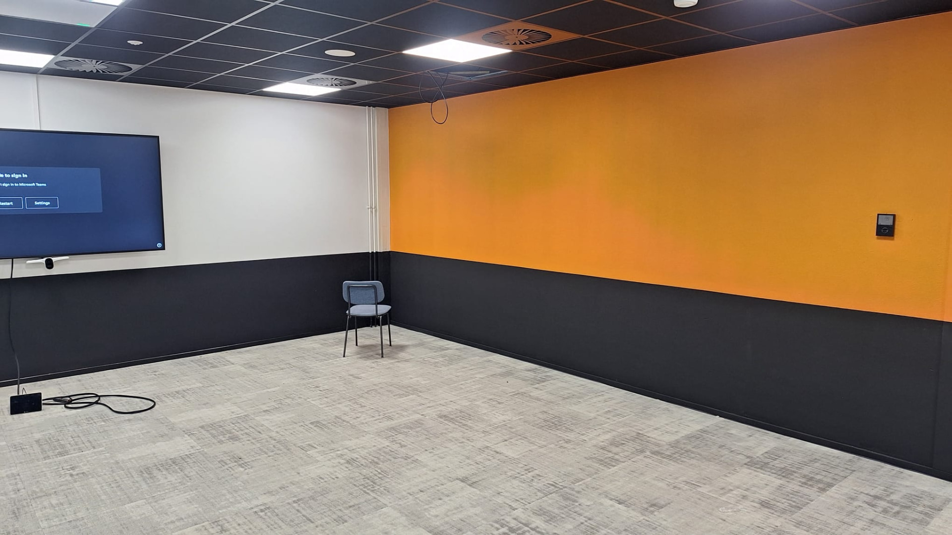 Vergaderruimte met oranje wand en donkere plint in twee kleuren