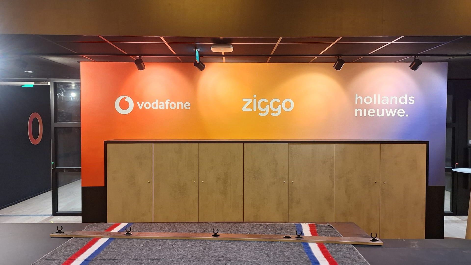 Gespoten merkwand met Vodafone, Ziggo en hollandsnieuwe logo's in de entree