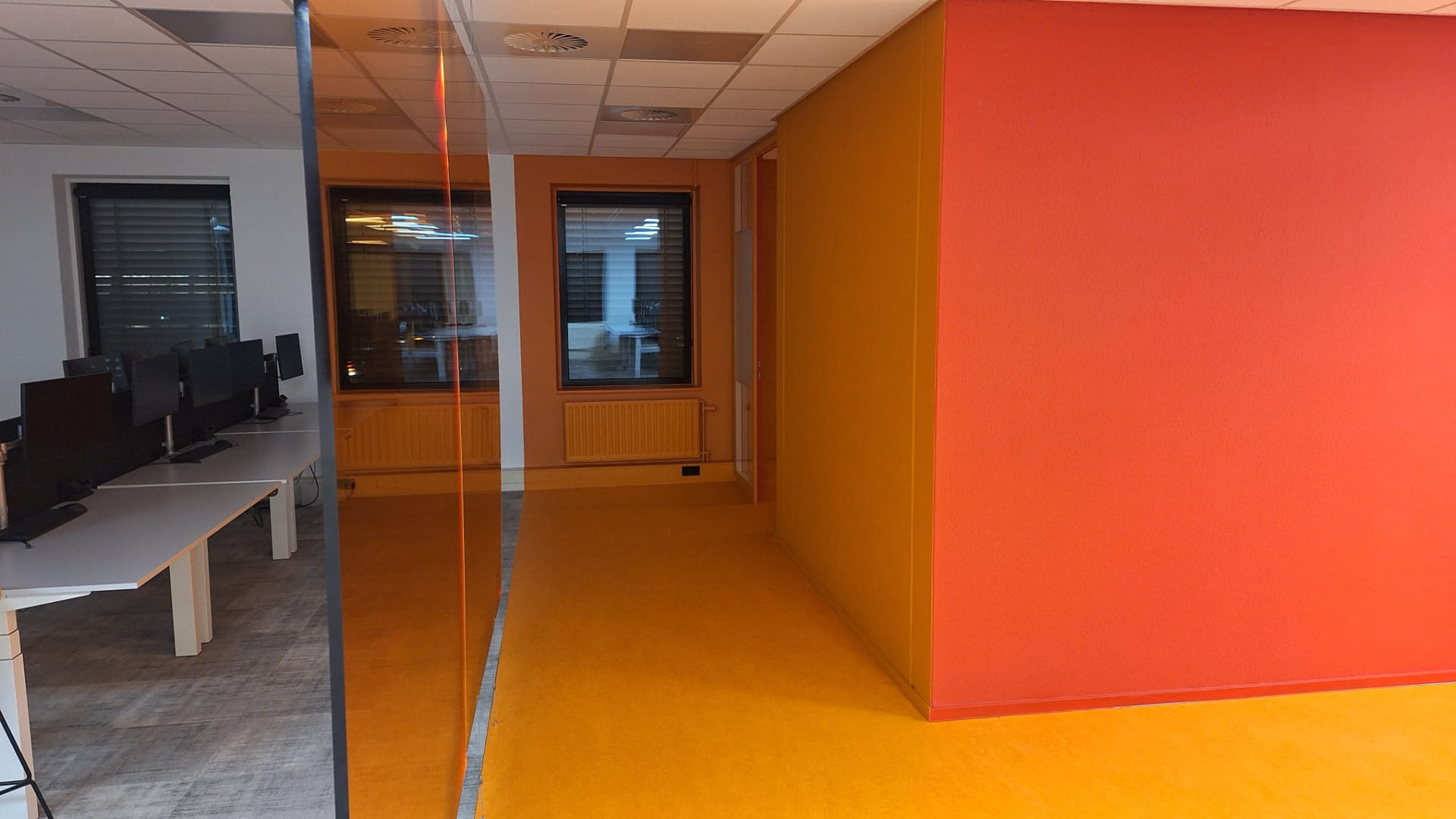 Airless gespoten oranje wanden in een open kantoorruimte